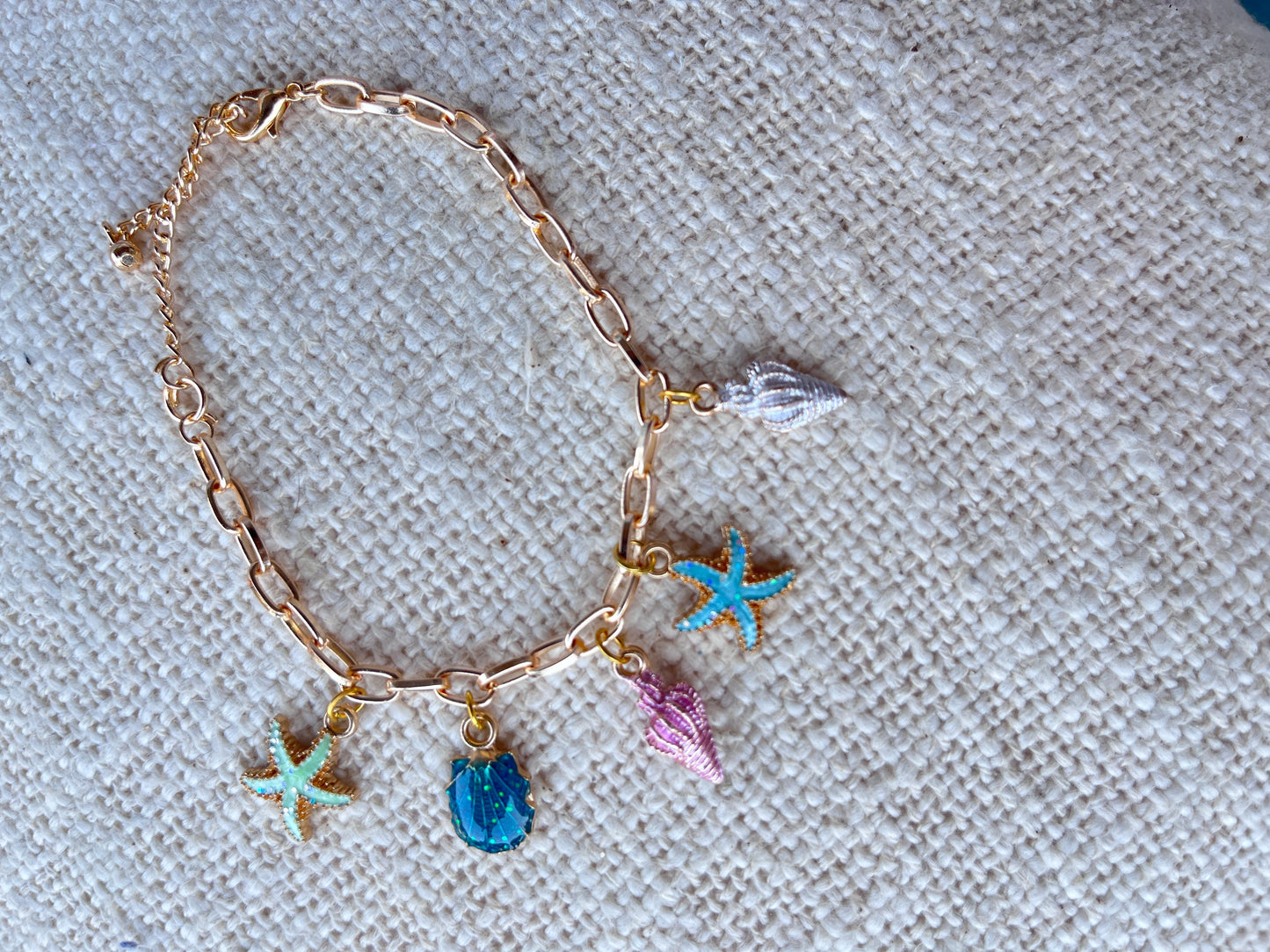 A gold bracelet with shell, star and conch shell charms