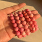 Image of a Carmine Conch Bracelet featuring spiral-shaped conch shells strung together on an elastic band