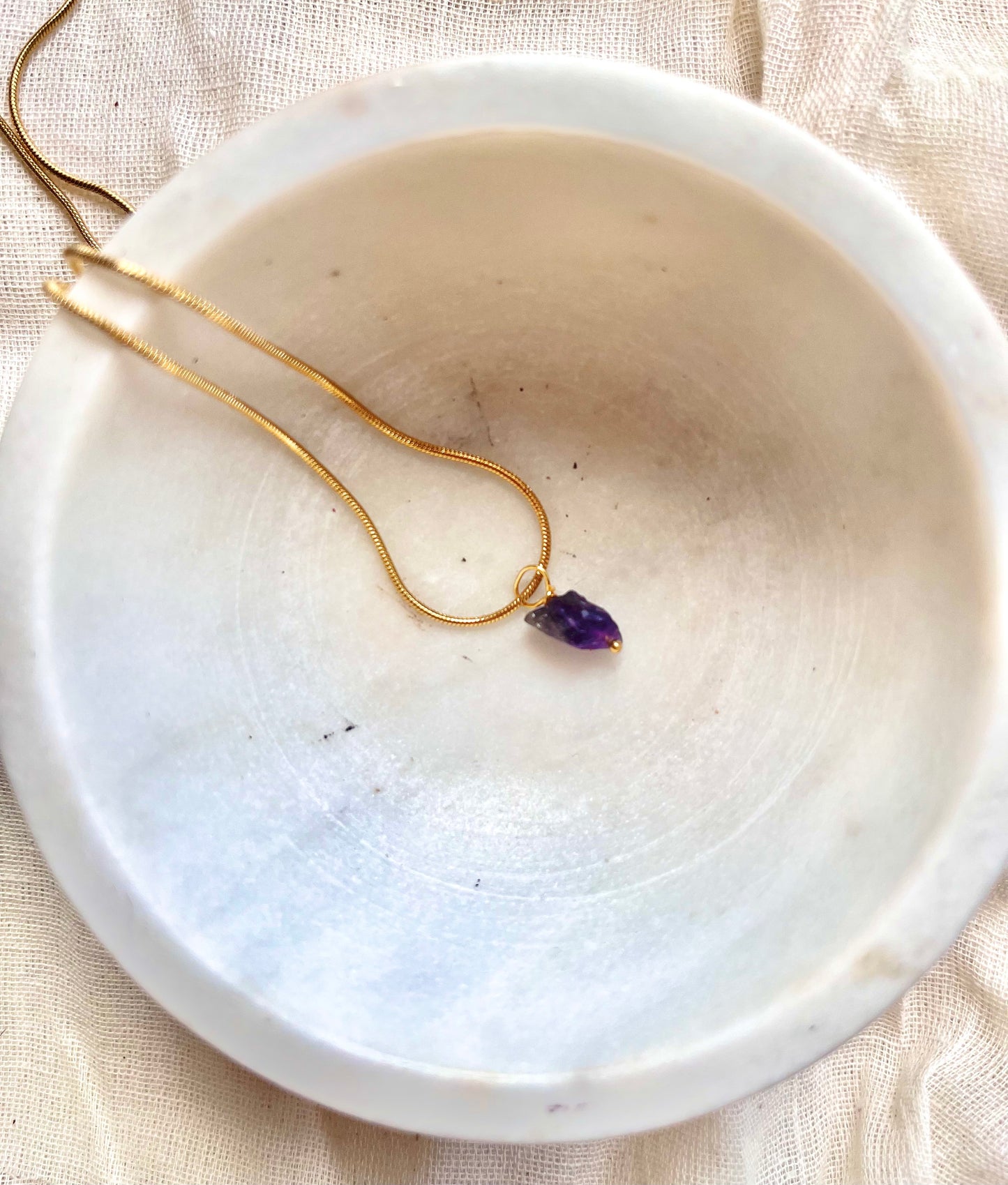 Amethyst necklace featuring a faceted purple gemstone pendant on a delicate gold chain