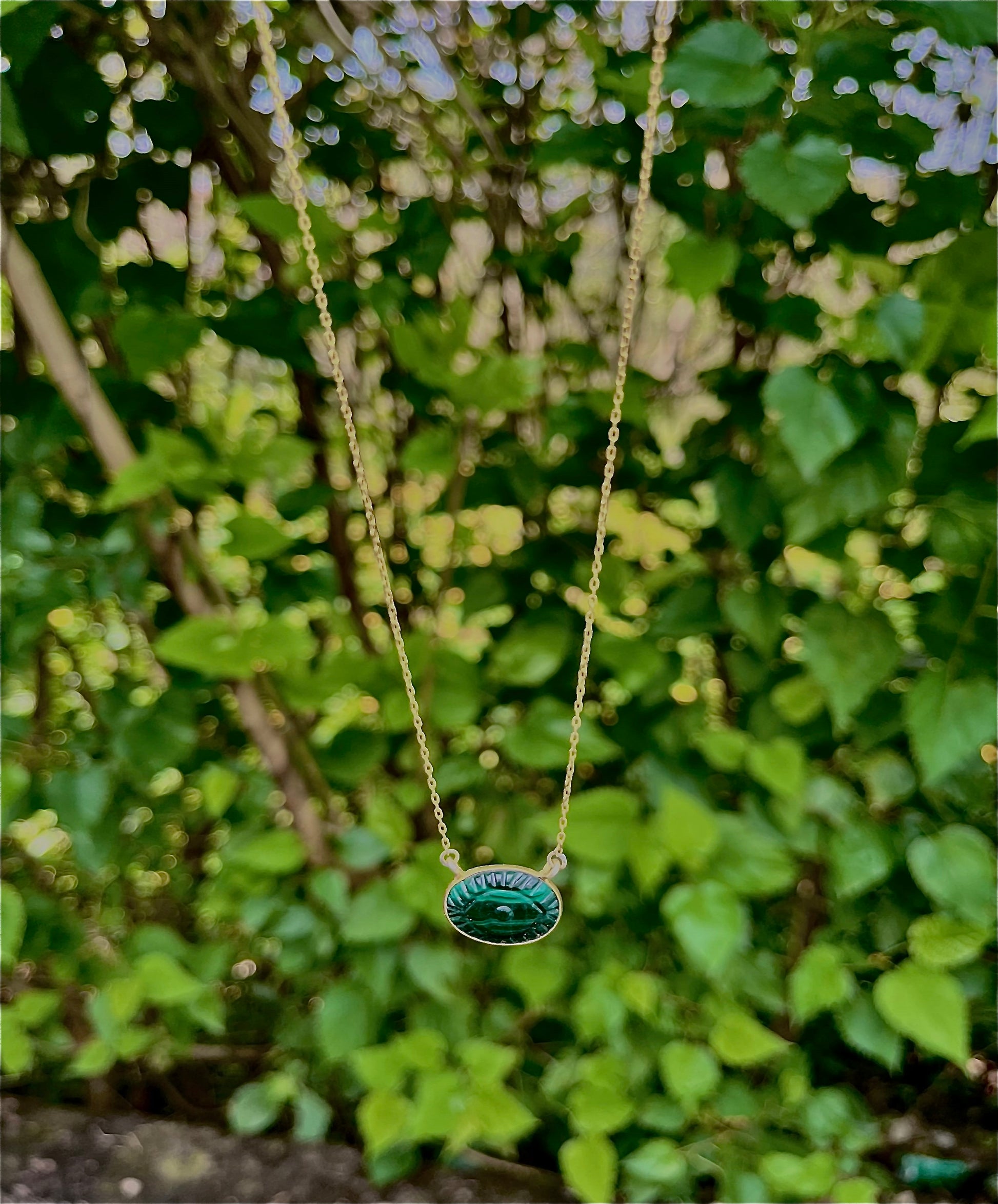 Malachite evil eye necklace featuring a green and black eye-shaped charm on a dainty gold chain