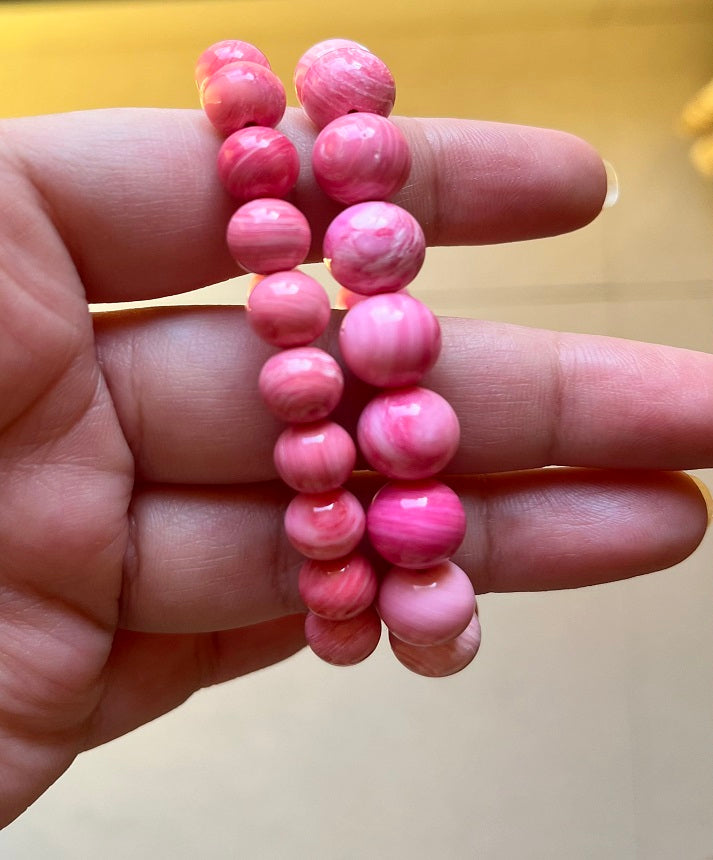 Image of a Carmine Conch Bracelet featuring spiral-shaped conch shells strung together on an elastic band