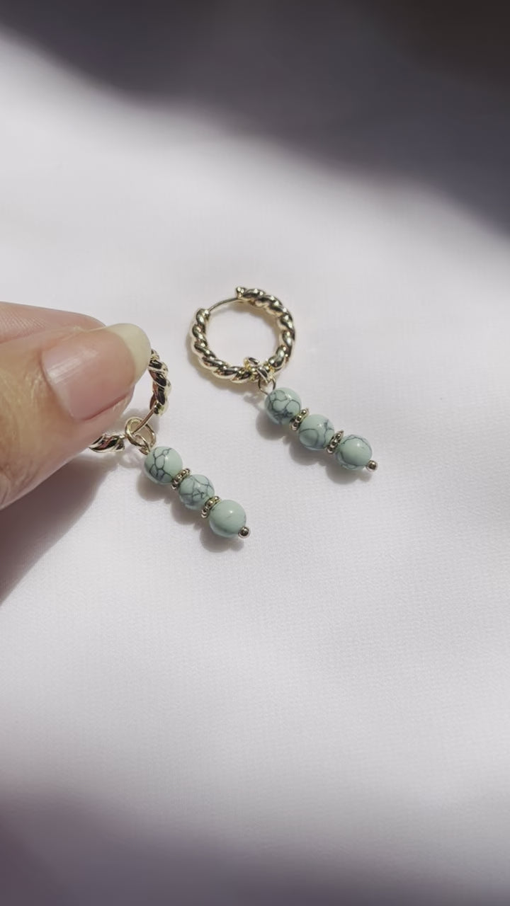 Turquoise huggies with small blue stones set in gold hoop earrings