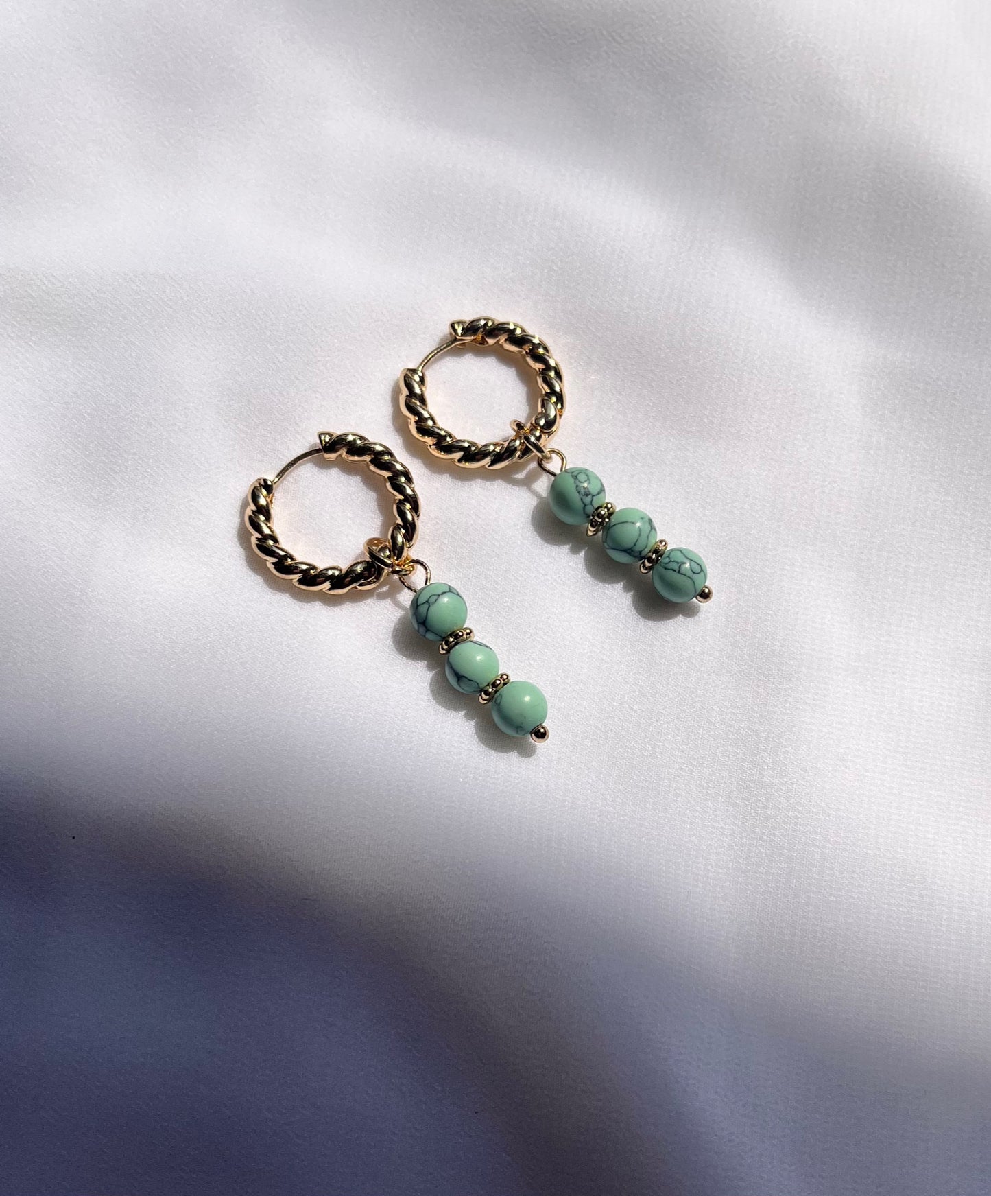 Turquoise huggies with small blue stones set in gold hoop earrings