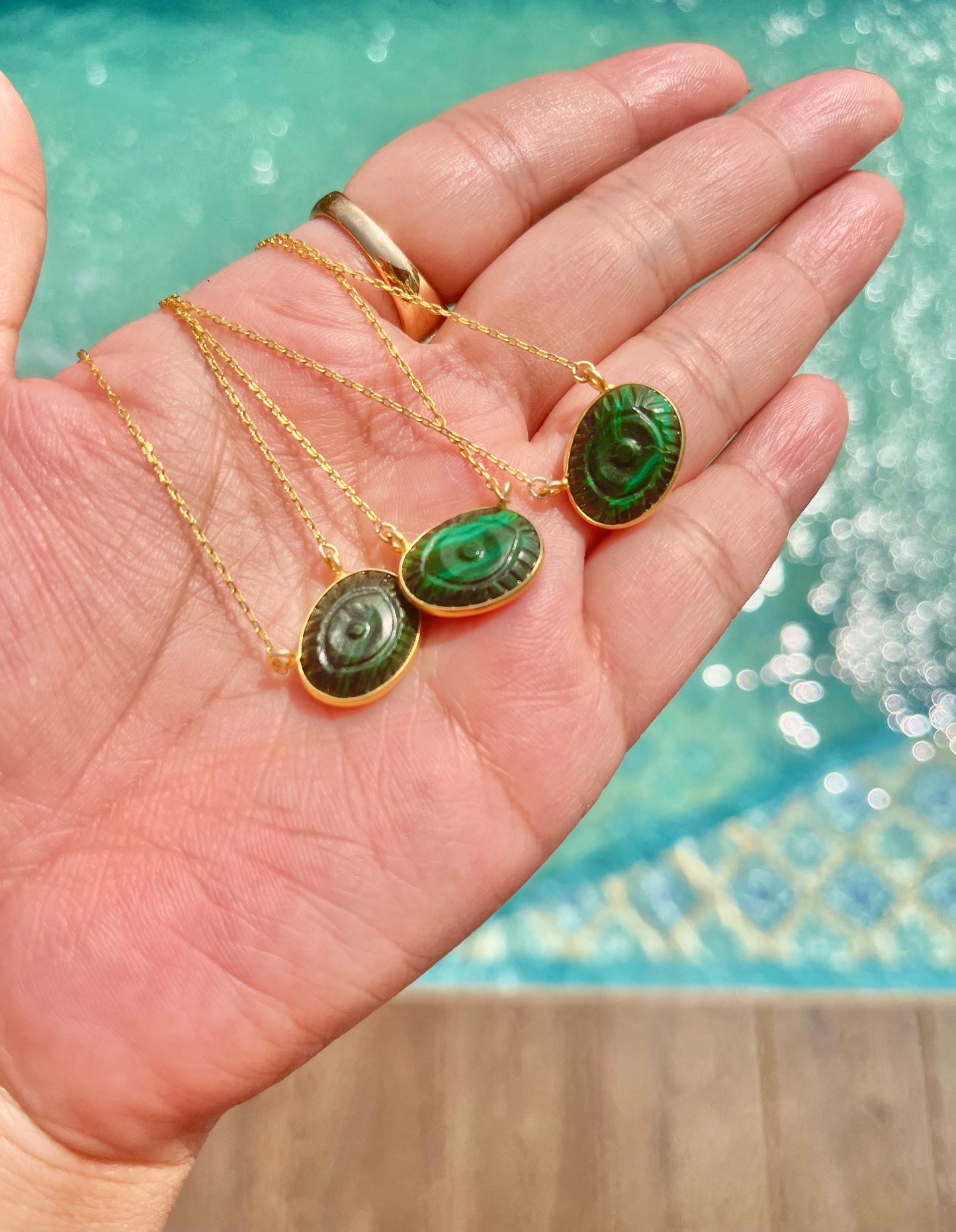 Malachite evil eye necklace featuring a green and black eye-shaped charm on a dainty gold chain